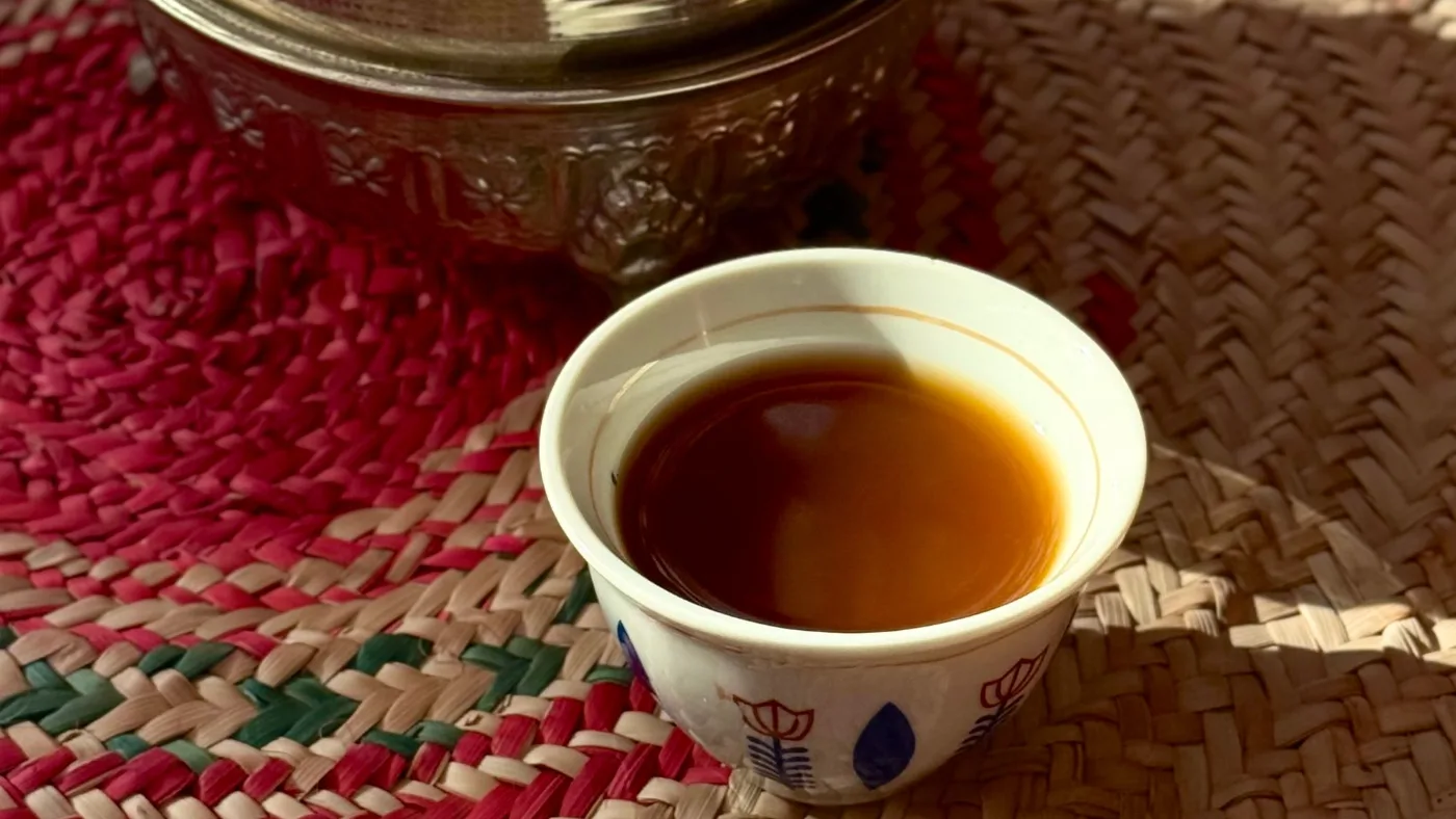 فنجان قهوة سعودية على حصير سدو بجانب الدلة